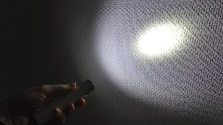 Xiaomi LED Taschenlampe Lichtkegel auf weißer Raufasertapete